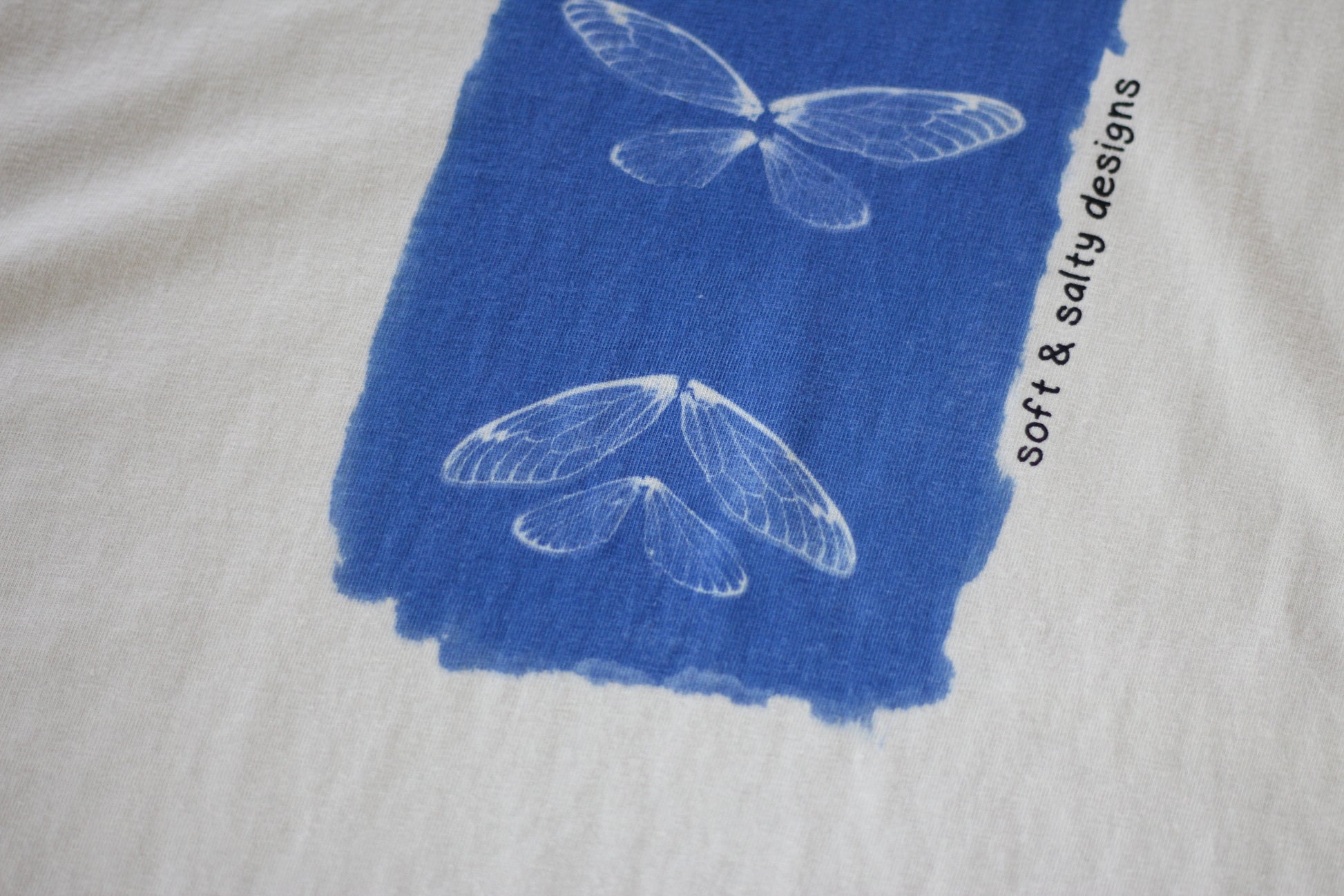 Close up of cicada wing silhouette hand-printed on an organic cotton t-shirt.