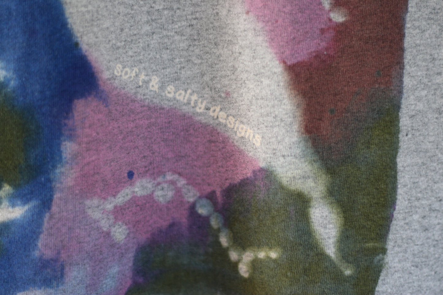Close-up of a fabric with colorful seaweed patterns and 'soft & saffy designs' text.