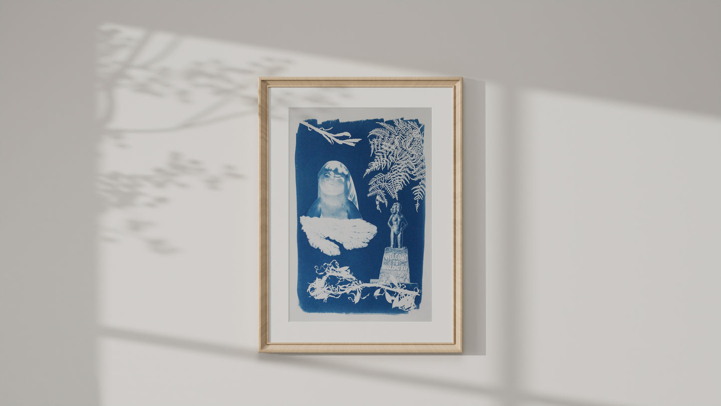 Framed art print of a cyanotype print featuring a dolphin, various seaweed pieces, a fern and the Syrena of Binalong Bay statue. 