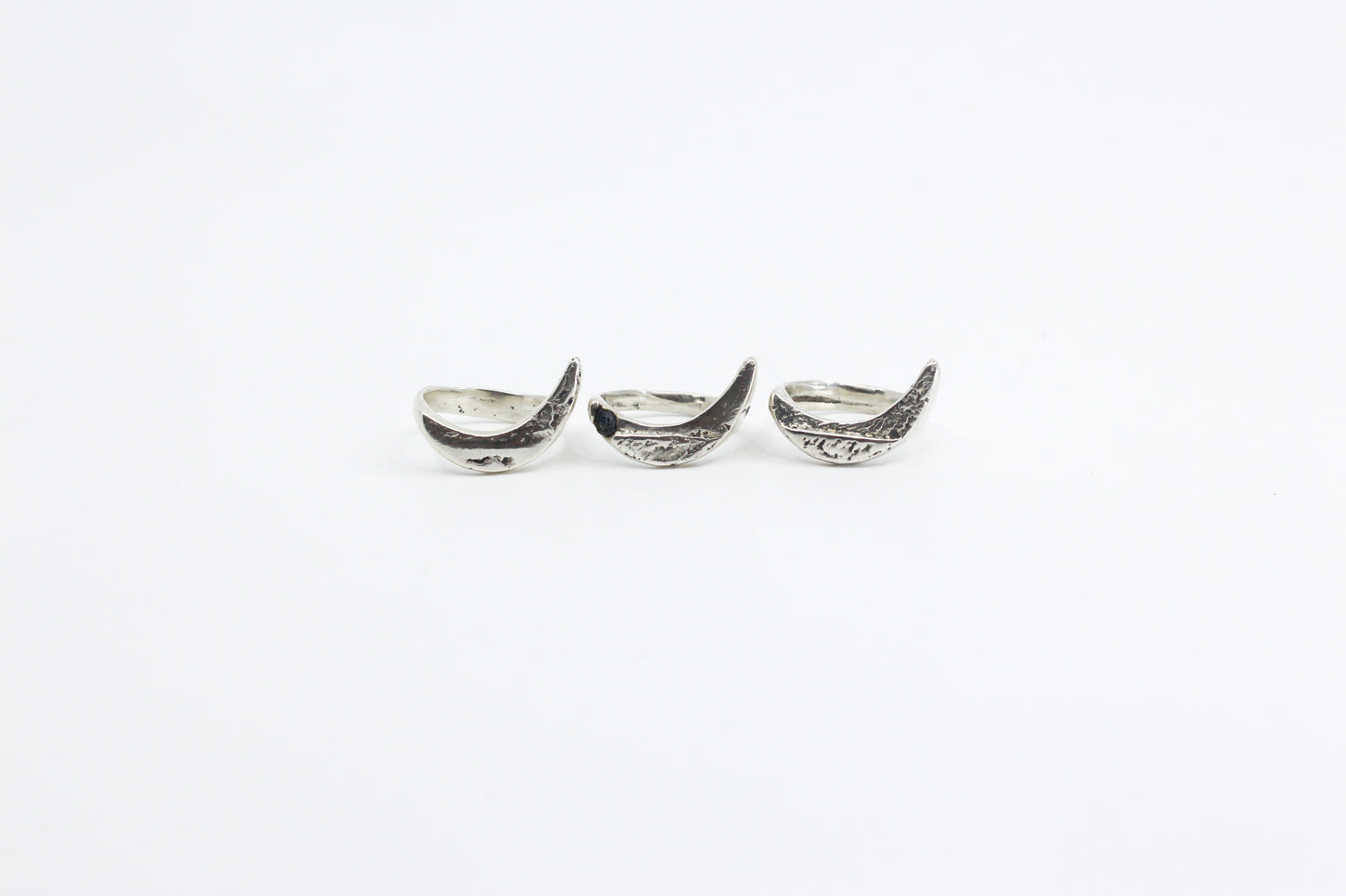 Three silver crescent moon-shaped rings on a white background
