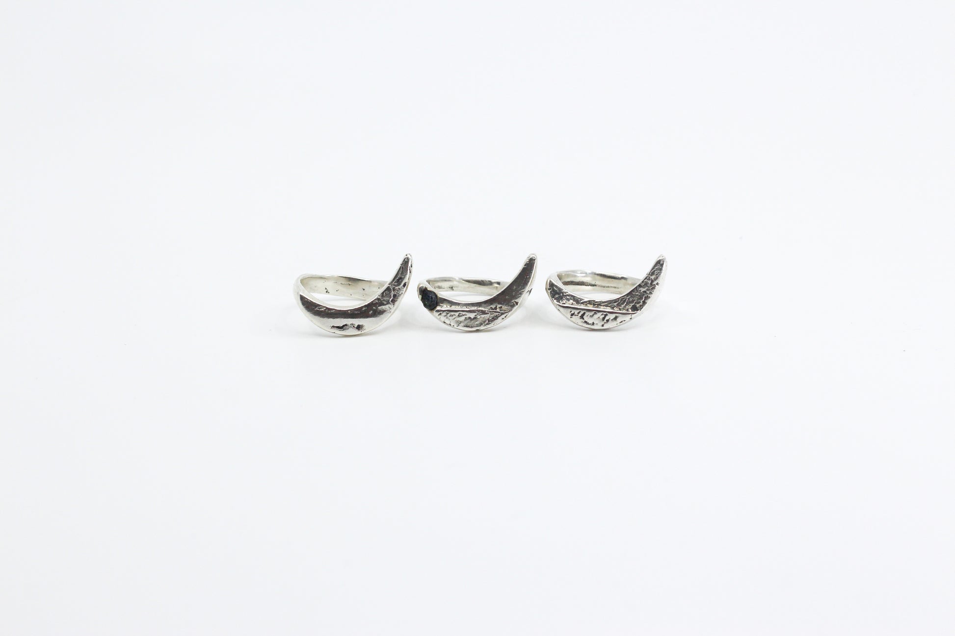 Three silver crescent moon-shaped rings on a white background