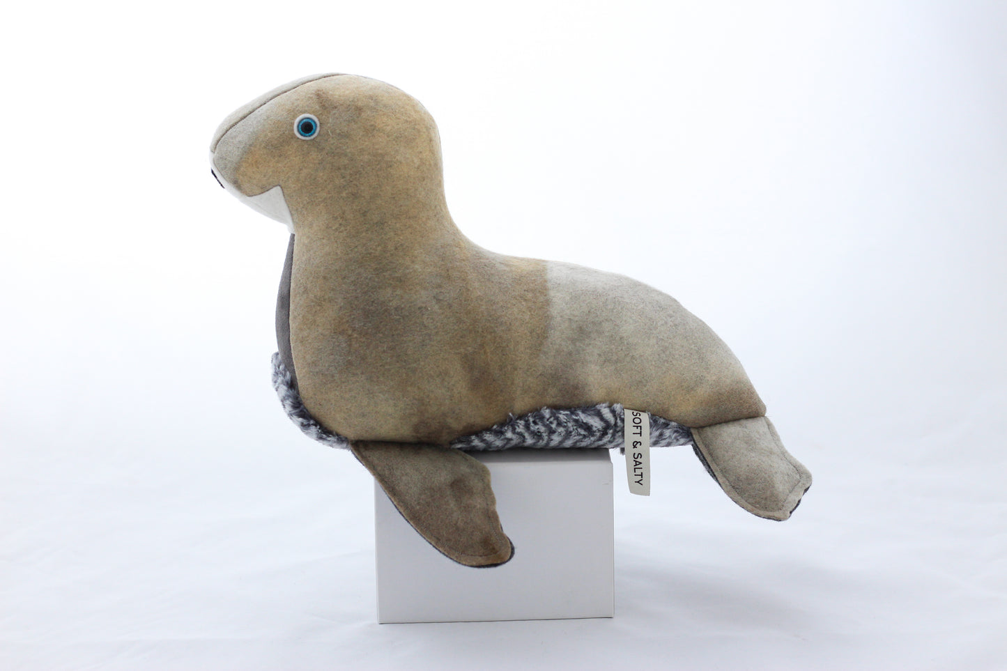 Plush seal toy on a white box with a white background