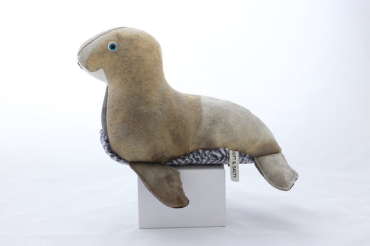 Plush seal toy on a white box with a white background