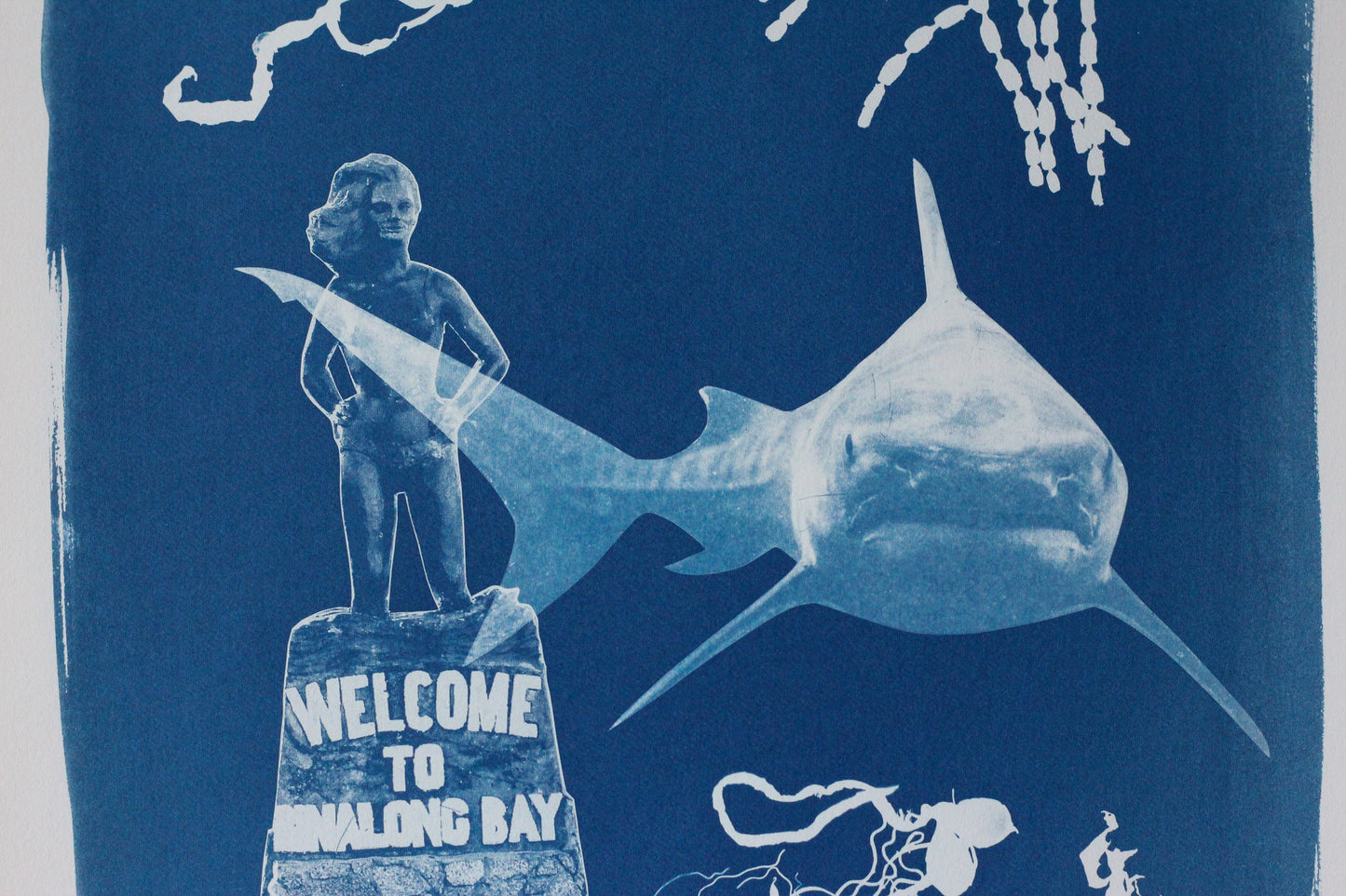 A blue and white cyanotype-style artwork featuring a shark, and the Syrena statue reading 'WELCOME TO BINALONG BAY,' and abstract marine elements on a dark blue background.