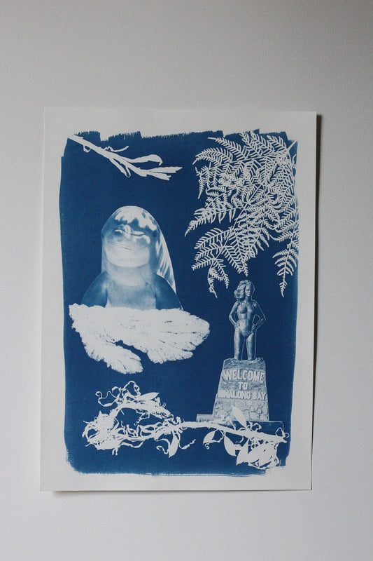 Cyanotype on paper artwork featuring a dolphin, various seaweed pieces, a fern and the Syrena of Binalong Bay statue. 