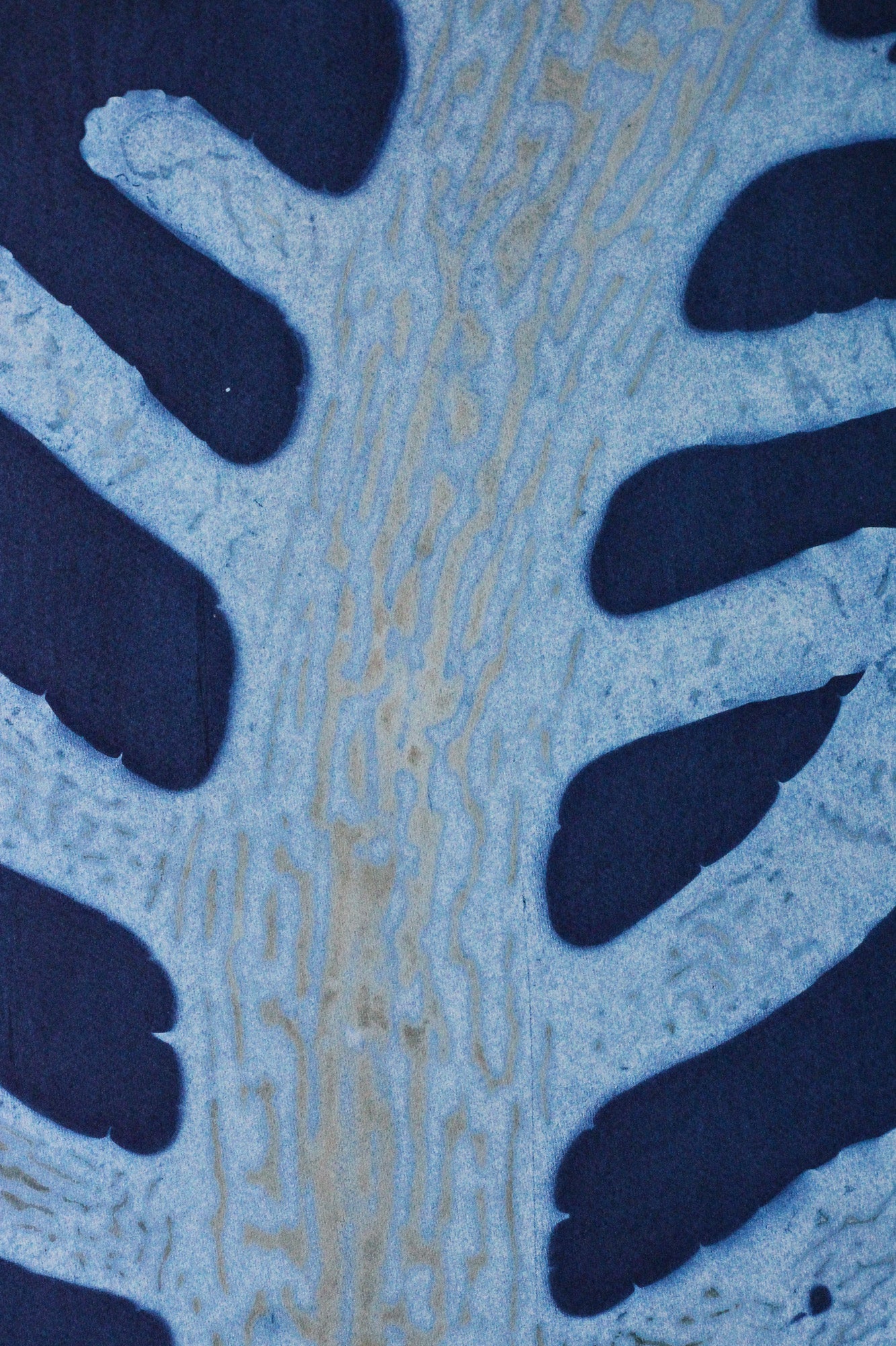 A close-up of a blue and navy patterned textile or material with a leaf-like or branch-like organic design.