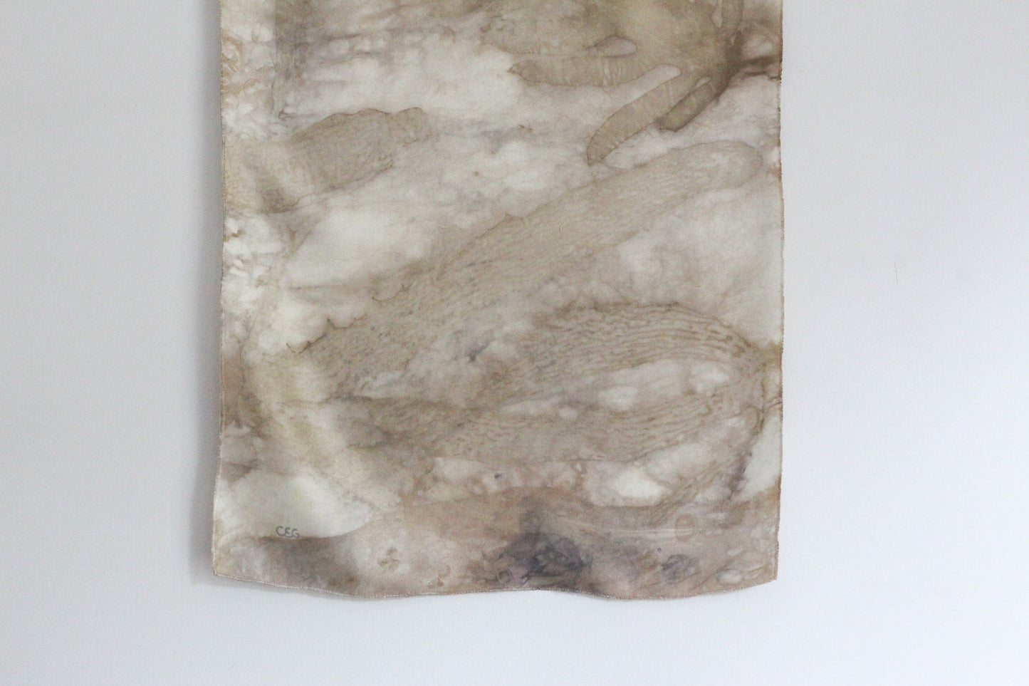 A rectangular textile wall hanging or panel with an abstract marbled pattern in beige, cream, taupe, and light brown tones, photographed against a plain white wall.